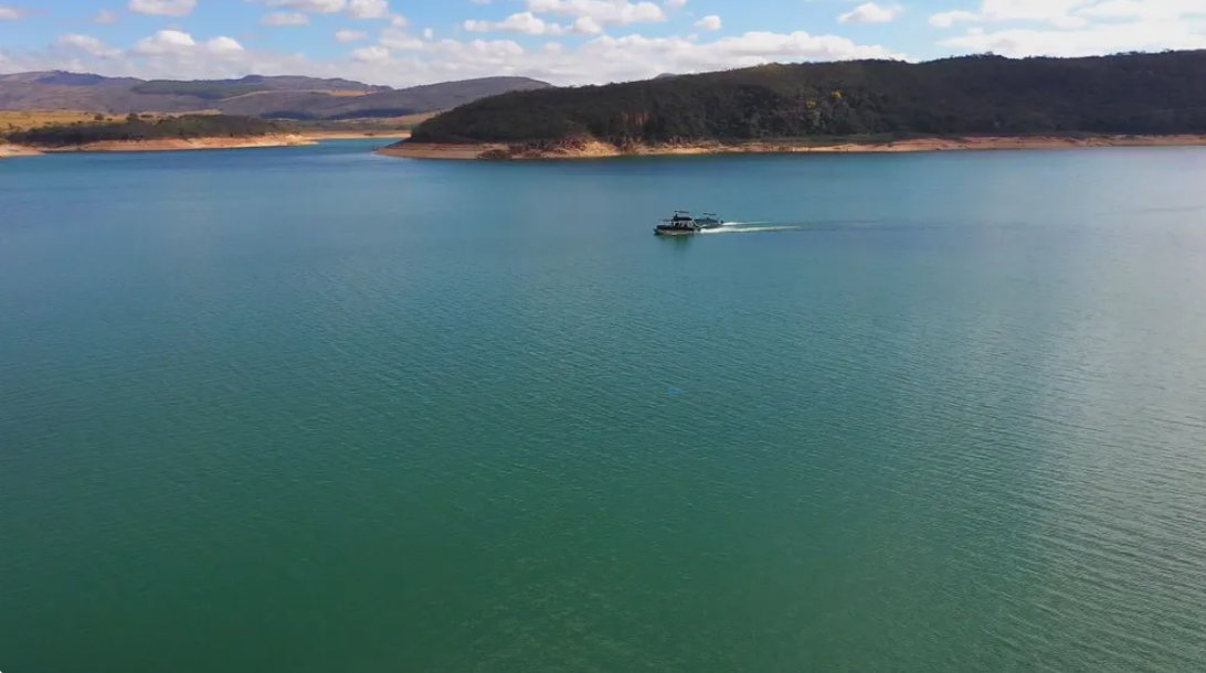 Vista aérea do Lago de Furnas, com barco navegando entre as montanhas da região